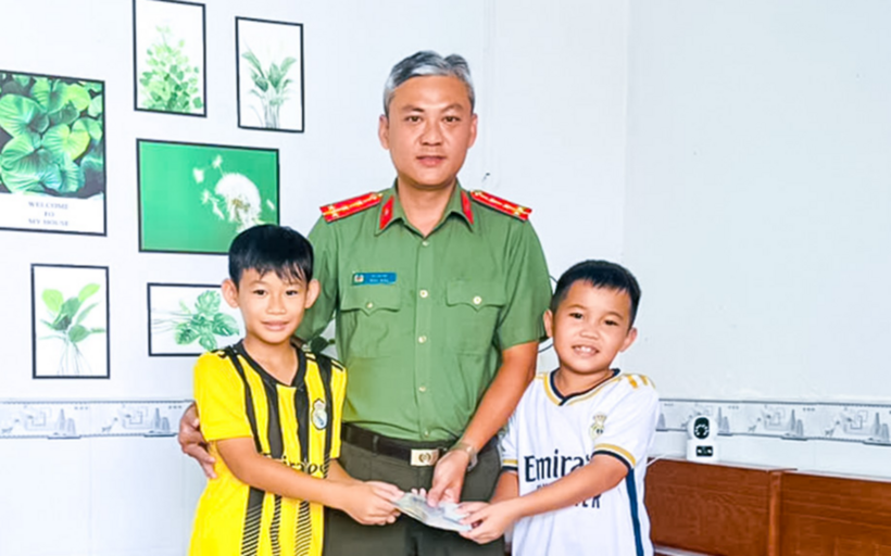Em Hồ Minh Tuệ (áo trắng) và em Lê Trần Thành Nhân (áo vàng) giao nộp số tiền nhặt được cho Công an phường An Xuyên để hỗ trợ tìm người đánh rơi. (Ảnh: Báo Cà Mau)