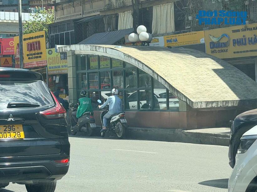 Nhiều người tham gia giao thông tấp vào lề đường có bóng râm để tránh nắng, chờ đèn đỏ trong điều kiện thời tiết oi bức.