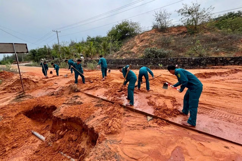 Lực lượng chức năng xã Phan Rí Cửa đang khẩn trương khắc phục điểm sạt lở, san gạt đất cát tràn xuống mặt đường. (Ảnh: Tiền phong)