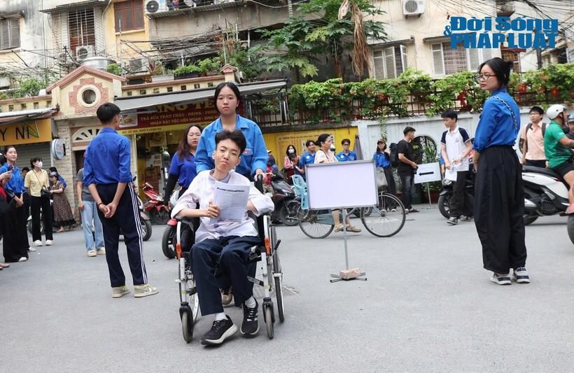 Sơn được tình nguyện viên hỗ trợ vào phòng thi bằng xe lăn