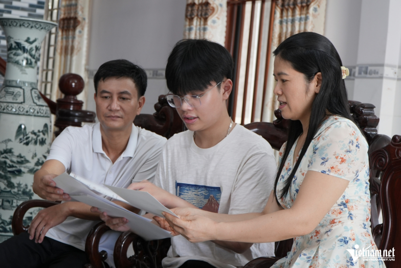 Vinh cùng bố mẹ xem lại thành tích em từng đạt. Ảnh:&nbsp;Hoàng Anh