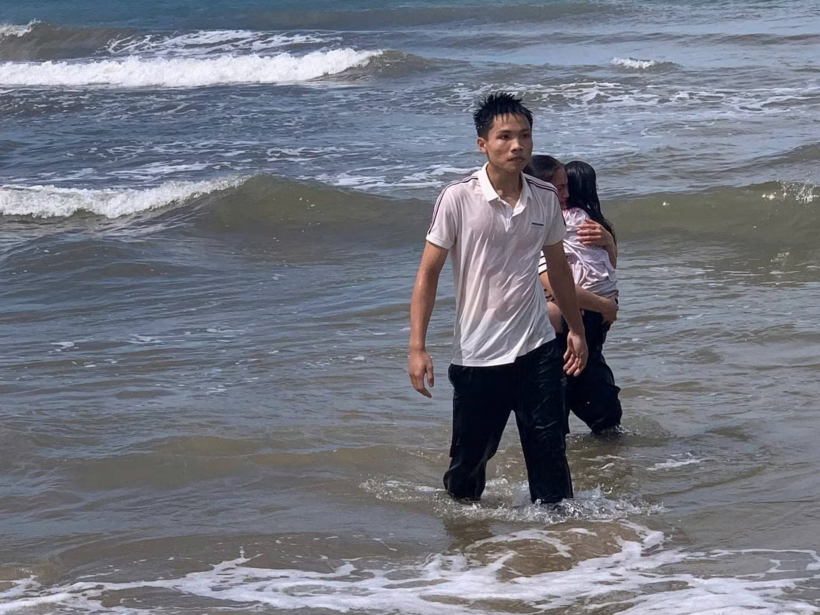 Trung mặc nguyên bộ quần áo đi du lịch và không ngần ngại lao ra biển cứu em nhỏ đuối nước. Ảnh: Công an Nhân dân