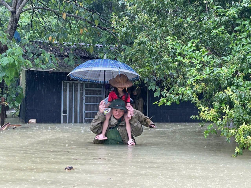 Lực lượng chức năng hỗ trợ người dân ra khỏi vùng ngập lụt. (Ảnh: VietnamNet)