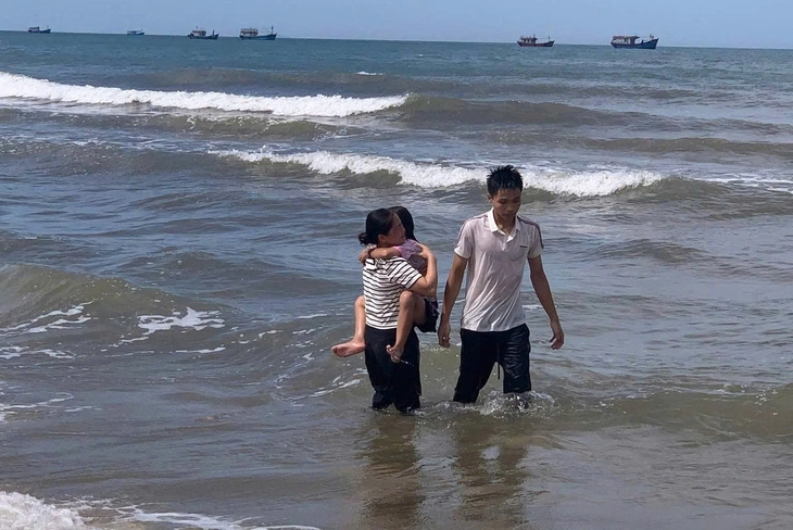 Trung tại thời điểm cứu bé gái vào bờ và đưa nạn nhân cho người mẹ. (Ảnh: Tuổi trẻ)