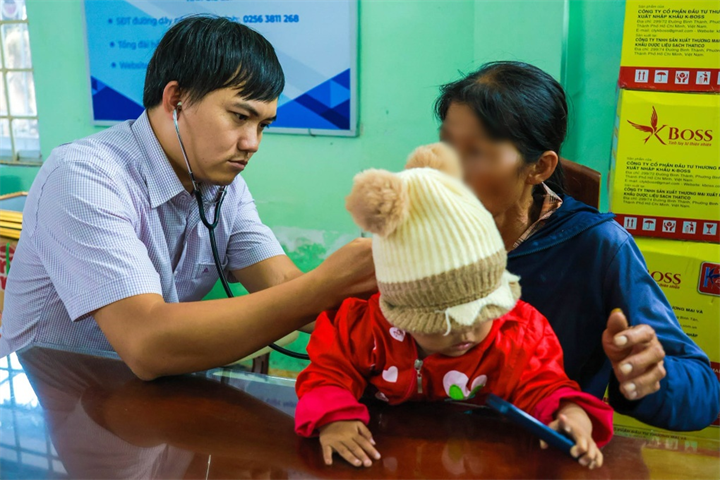 Cán bộ y tế kiểm tra sức khỏe cho cháu bé trước khi gia đình đưa về quê. Ảnh: Dân trí