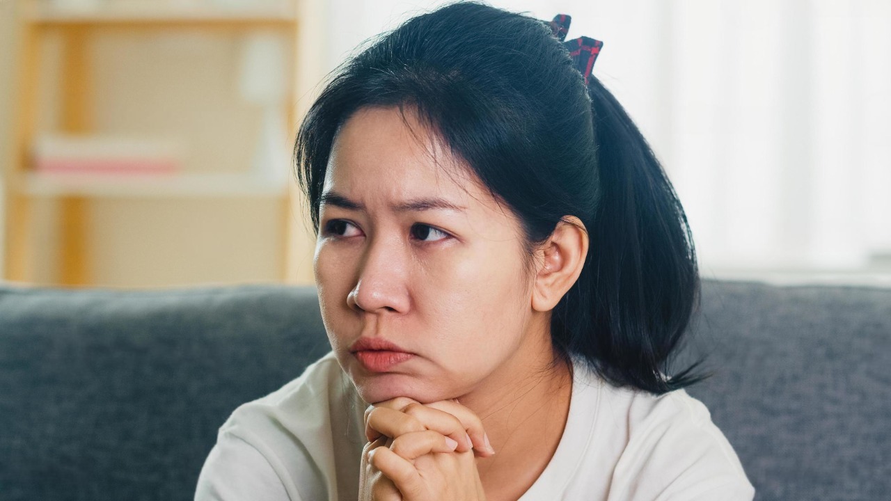 depressed crying asian business woman stressed with headache sitting on sofa in living room at house when social distancing stay at home and self quarantine time coronavirus concept photo