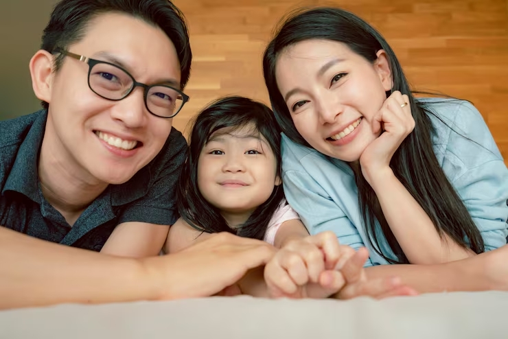 happiness joyful asian family mom dad daughter laydown together with fun play kiss bed portrait asia