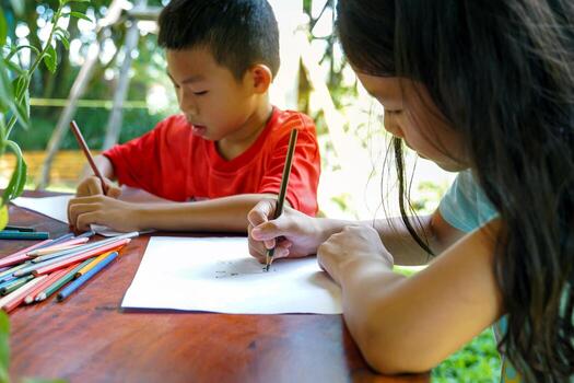 asian children are happy to draw their imaginations and paint with crayons in their spare time at home during school holidays soft and selective focus photo