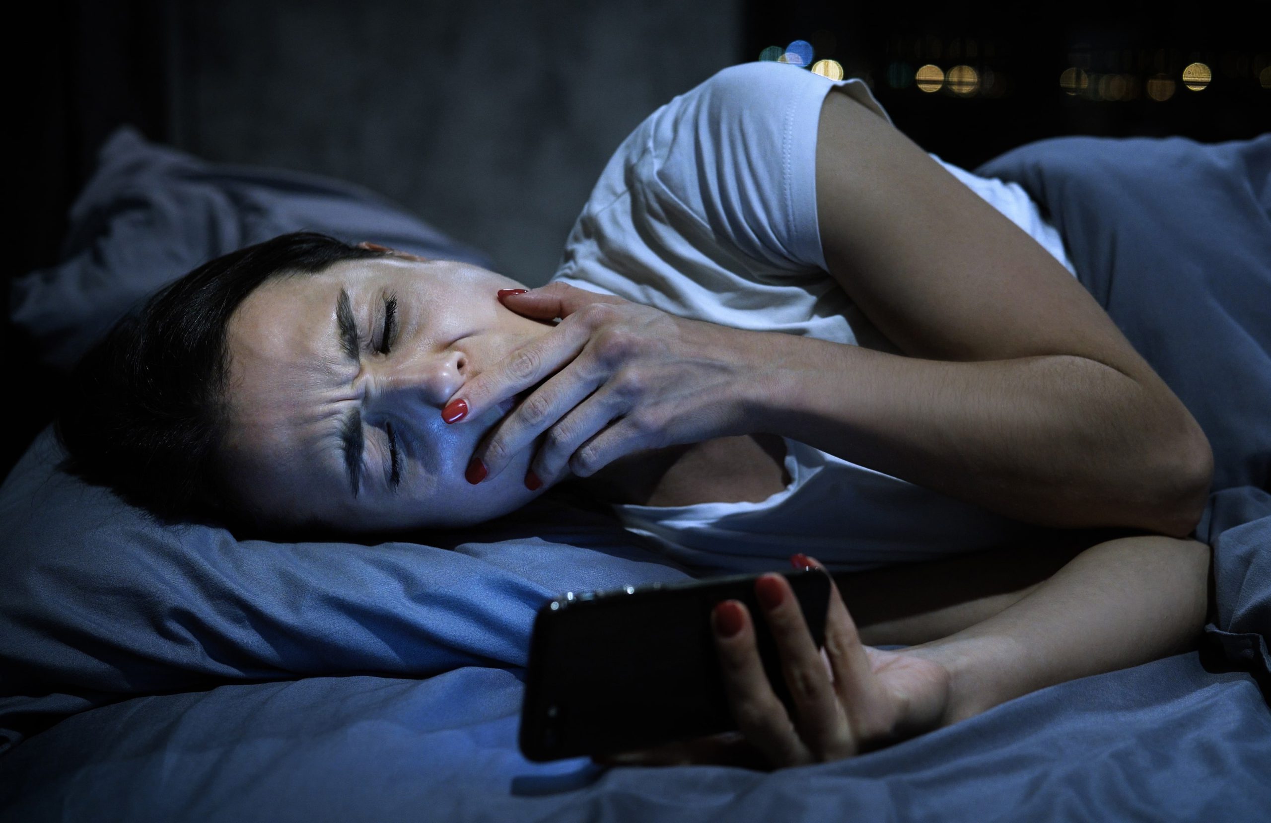 young sleepy attractive woman with mobile phone ly 2021 12 09 21 20 53 utc min scaled