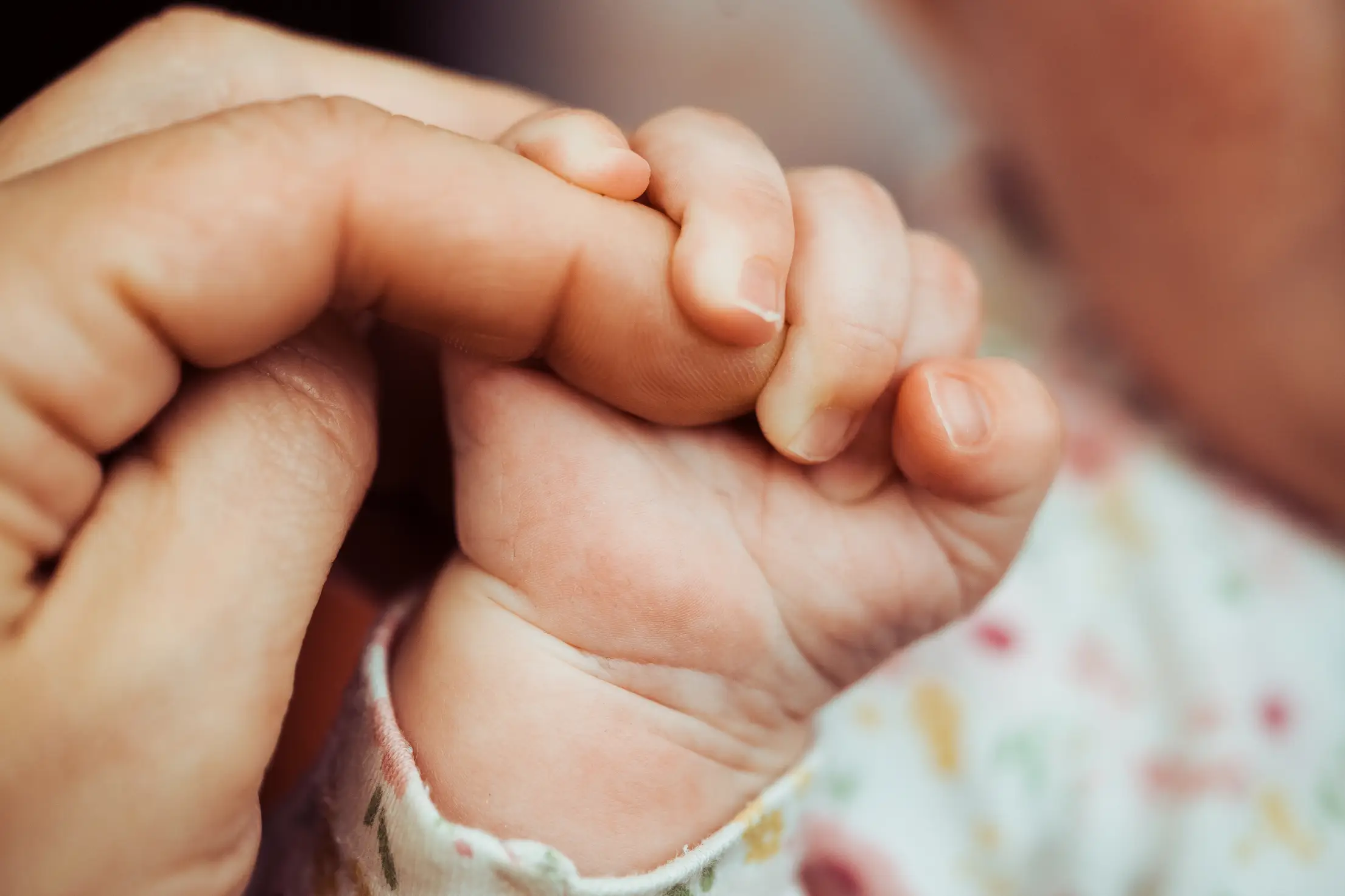 newborn baby holding adult finger