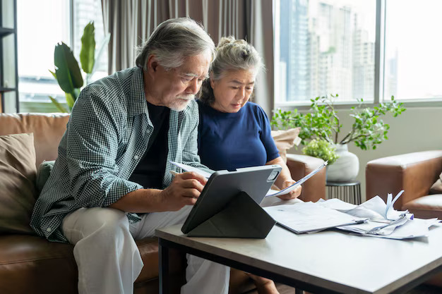 old retired asian senior couple checking calculate financial billing together sofa involved financial paperwork paying taxes online using ebanking laptop living room home background609648 190