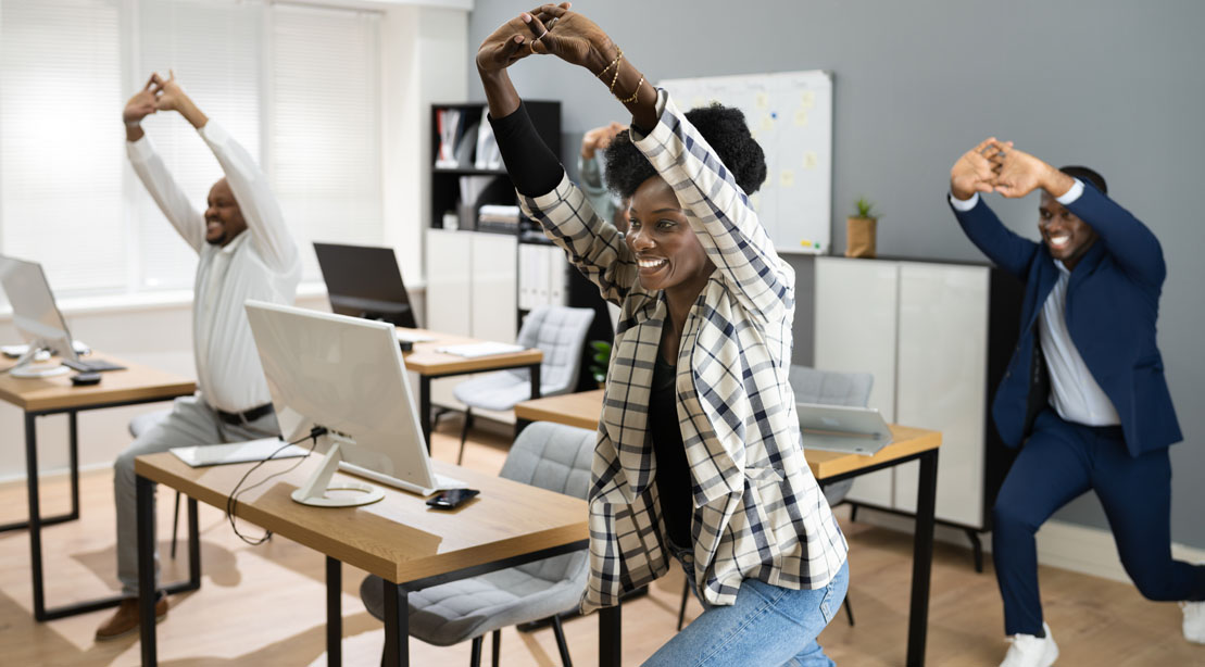 office workers performing anti sitting exercises and workout at their desks