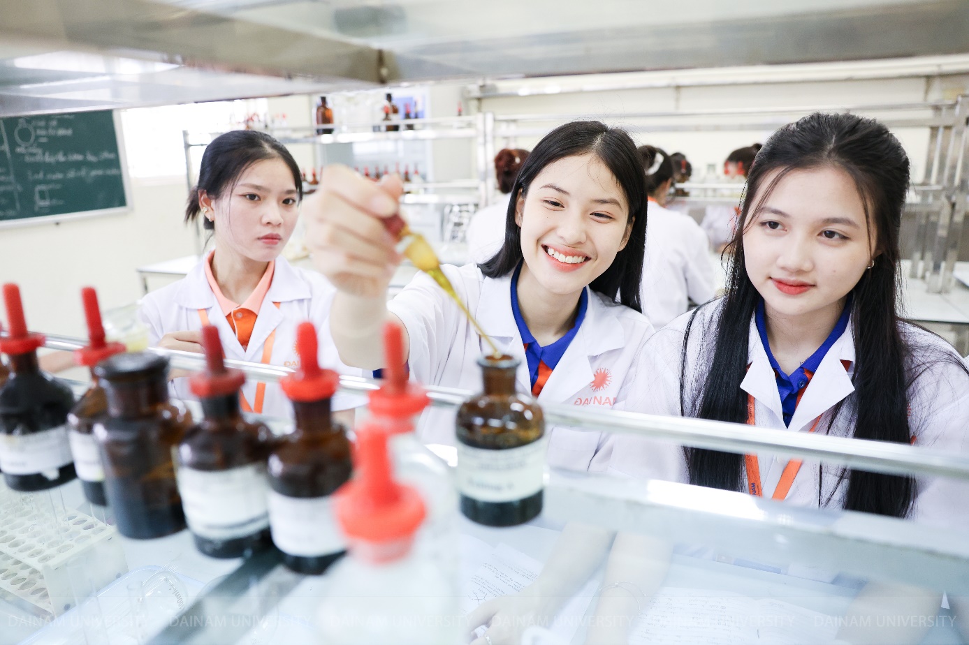 A group of women in lab coats pouring liquid into bottles Description automatically generated