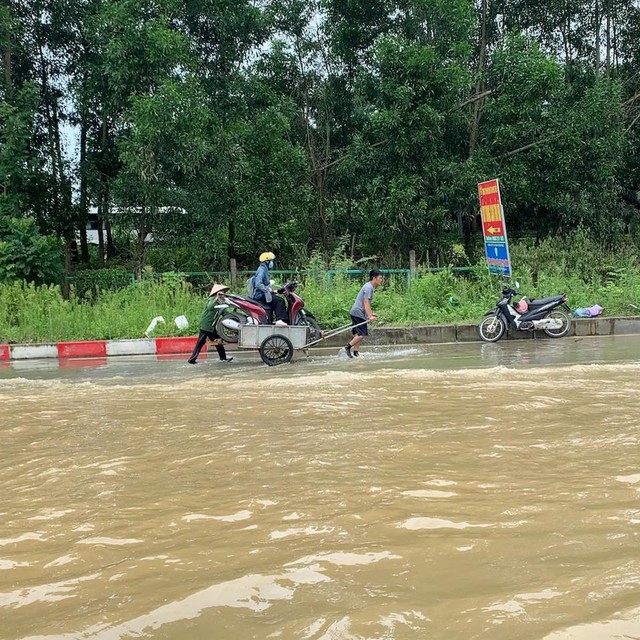 Tấm biển "lạ" giữa làn nước ngập ở đại lộ Thăng Long của 3 chú cháu: Đứng suốt 5 tiếng không thấy mỏi chân- Ảnh 3.