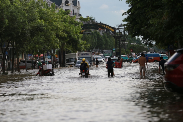 Trời hửng nắng, nhiều tuyến đường ở Hà Nội vẫn ngập sâu, người dân dùng tấm chắn để ngăn nước tràn vào nhà- Ảnh 1. Trời hửng nắng, nhiều tuyến đường ở Hà Nội vẫn ngập sâu, người dân dùng tấm chắn để ngăn nước tràn vào nhà- Ảnh 1.
