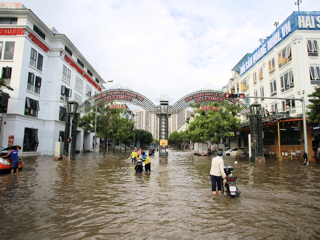 Trời hửng nắng, nhiều tuyến đường ở Hà Nội vẫn ngập sâu, người dân dùng tấm chắn để ngăn nước tràn vào nhà- Ảnh 2. Trời hửng nắng, nhiều tuyến đường ở Hà Nội vẫn ngập sâu, người dân dùng tấm chắn để ngăn nước tràn vào nhà- Ảnh 2.