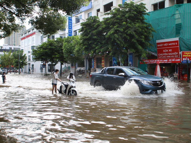 Trời hửng nắng, nhiều tuyến đường ở Hà Nội vẫn ngập sâu, người dân dùng tấm chắn để ngăn nước tràn vào nhà- Ảnh 13.