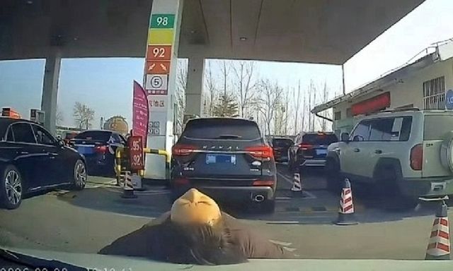 Clip: Sững sờ cảnh người phụ nữ nằm đè lên capo xe ô tô để tranh chỗ đổ xăng