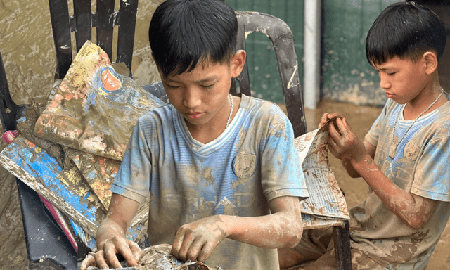 Cậu bé 12 tuổi lật từng trang sách lấm bùn sau lũ quét ở Nghệ An: “Chữ vẫn còn đọc được cô ạ!”