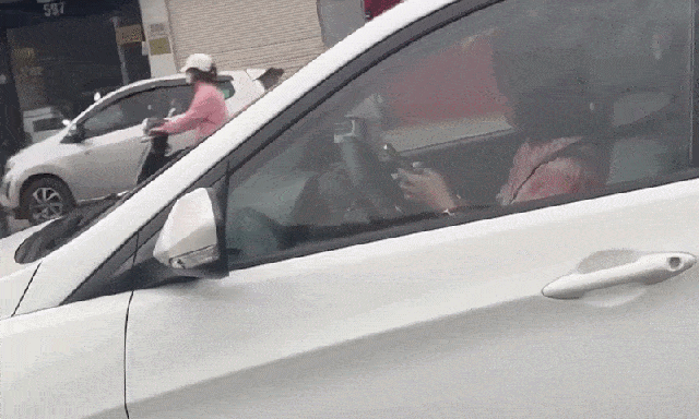 Nữ tài xế dùng 2 tay bấm điện thoại trong lúc đang lái xe trên phố Hà Nội