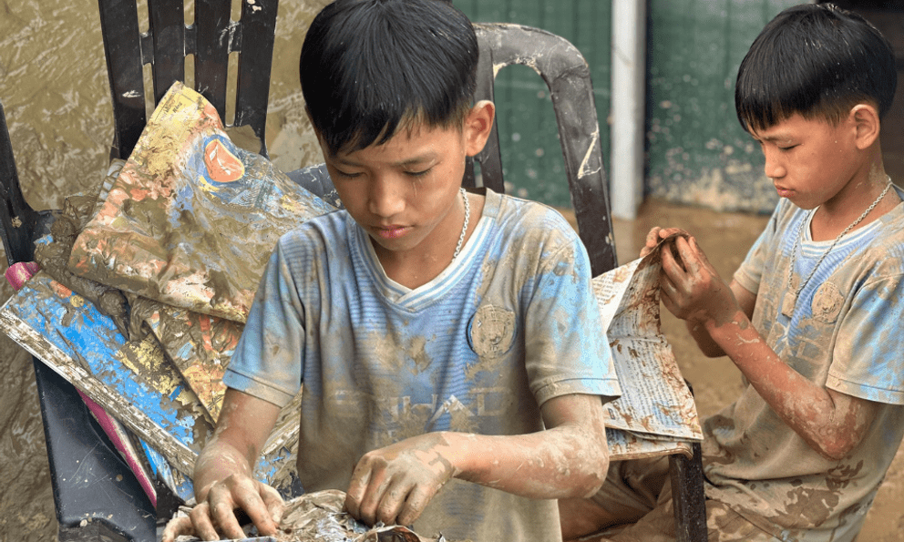 Cậu bé 12 tuổi lật từng trang sách lấm bùn sau lũ quét ở Nghệ An: “Chữ vẫn còn đọc được cô ạ!”